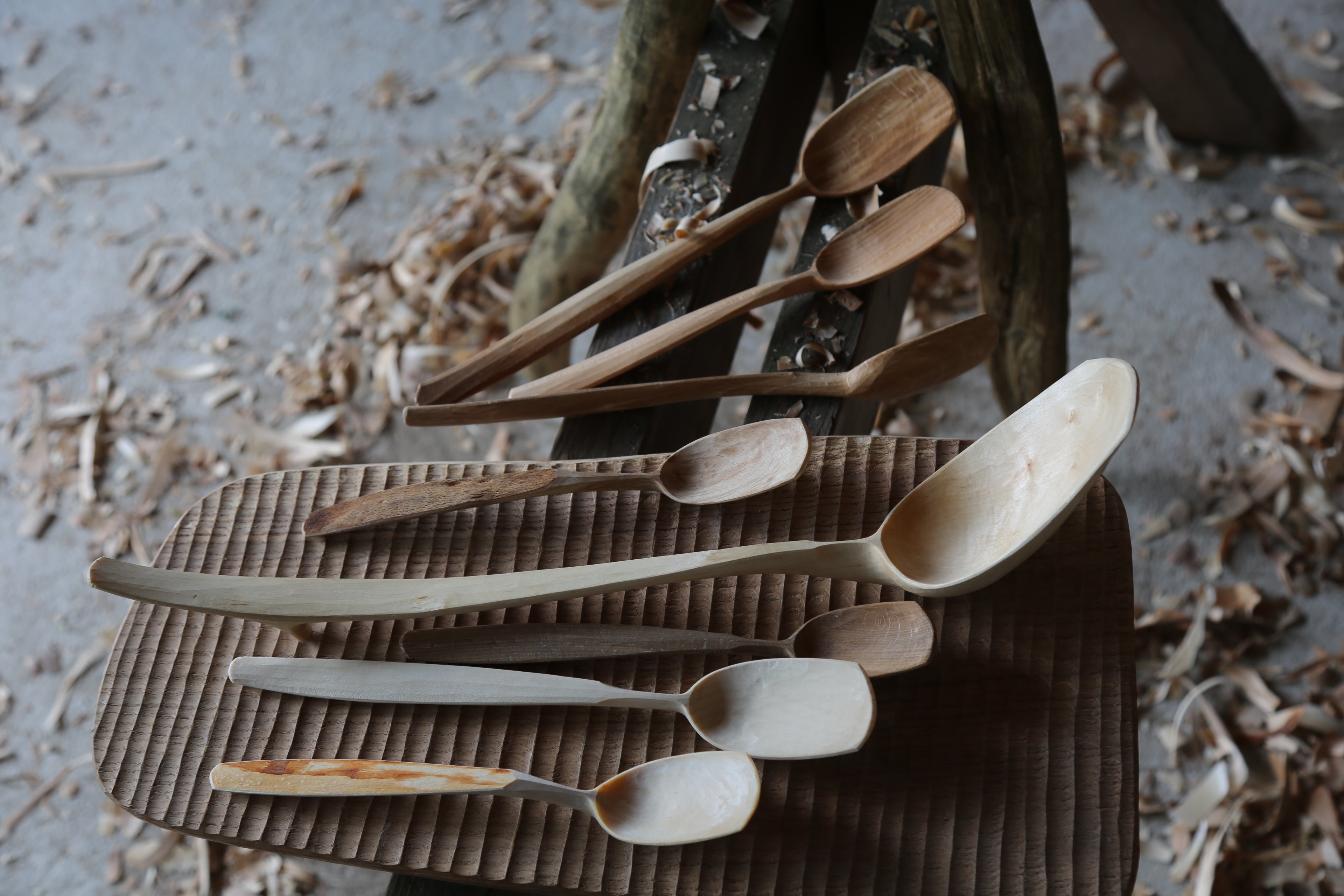 a perfect mixture of wooden spoons sat ontop of a textured oak board. the eating spoons nestled into the Lovely big ladles create a gorgeous scene